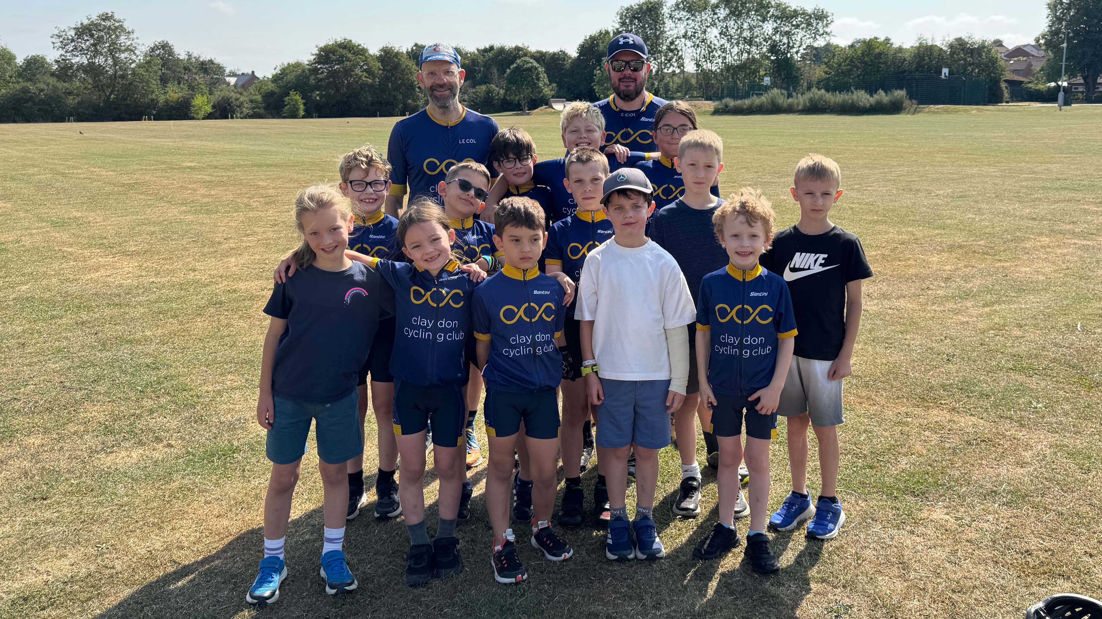 Youth riders and coaches posing together on a grass field